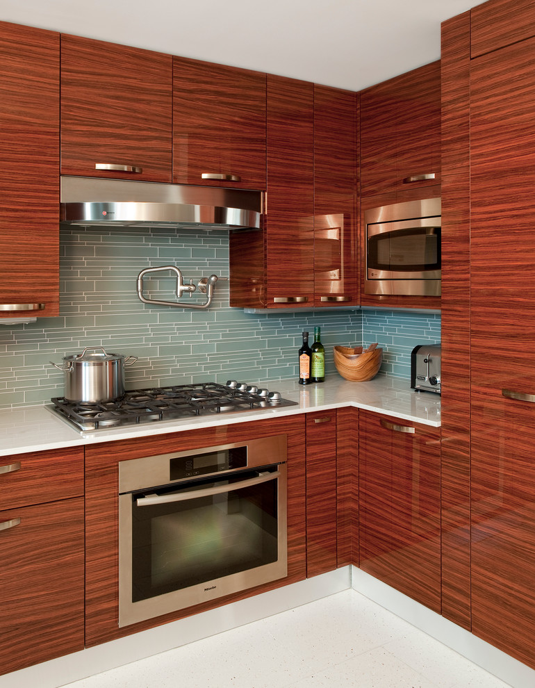 This is an example of a large contemporary u-shaped enclosed kitchen in New York with flat-panel cabinets, dark wood cabinets, green splashback, glass tiled splashback, stainless steel appliances, a submerged sink, marble worktops, terrazzo flooring and no island.