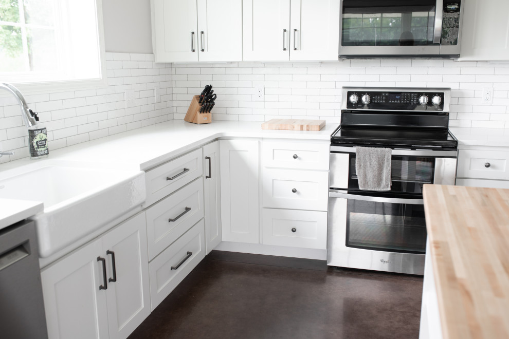Inredning av ett lantligt mellanstort vit vitt kök, med en rustik diskho, skåp i shakerstil, vita skåp, bänkskiva i kvarts, vitt stänkskydd, stänkskydd i keramik, rostfria vitvaror, betonggolv, en köksö och brunt golv