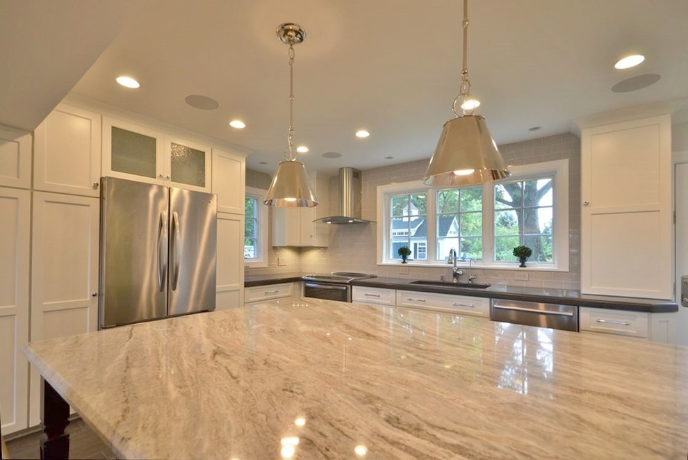 Classic kitchen/diner in DC Metro with a single-bowl sink, flat-panel cabinets, white cabinets, engineered stone countertops, glass tiled splashback, stainless steel appliances, porcelain flooring and an island.