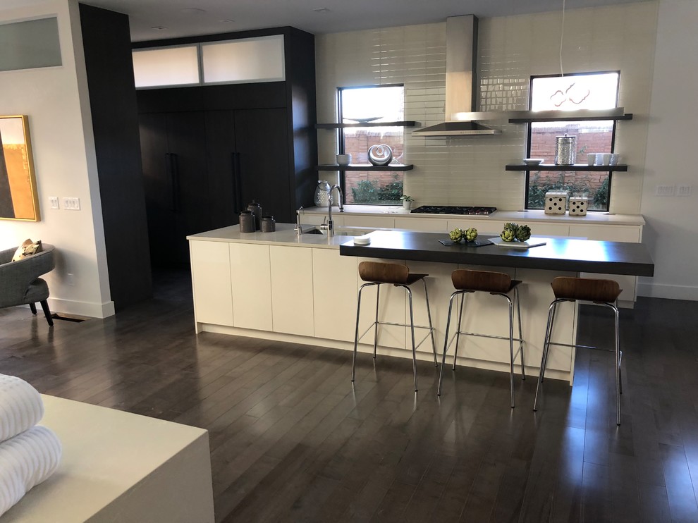 Exempel på ett mellanstort modernt kök, med en undermonterad diskho, släta luckor, vita skåp, rostfria vitvaror, mörkt trägolv, en köksö och brunt golv