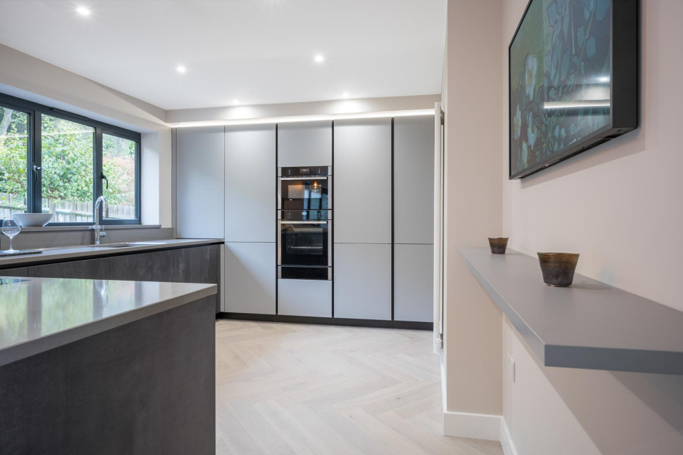 Inspiration for a contemporary open plan kitchen in Kent with grey cabinets, an island and white worktops.