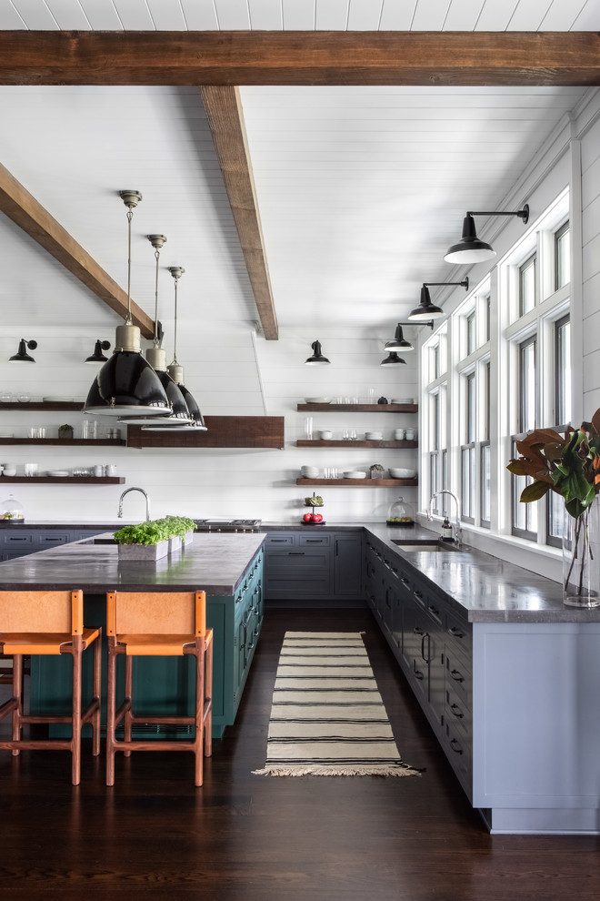 Foto på ett stort lantligt grå kök, med en undermonterad diskho, luckor med infälld panel, grå skåp, bänkskiva i betong, vitt stänkskydd, stänkskydd i trä, integrerade vitvaror, mörkt trägolv, en köksö och brunt golv