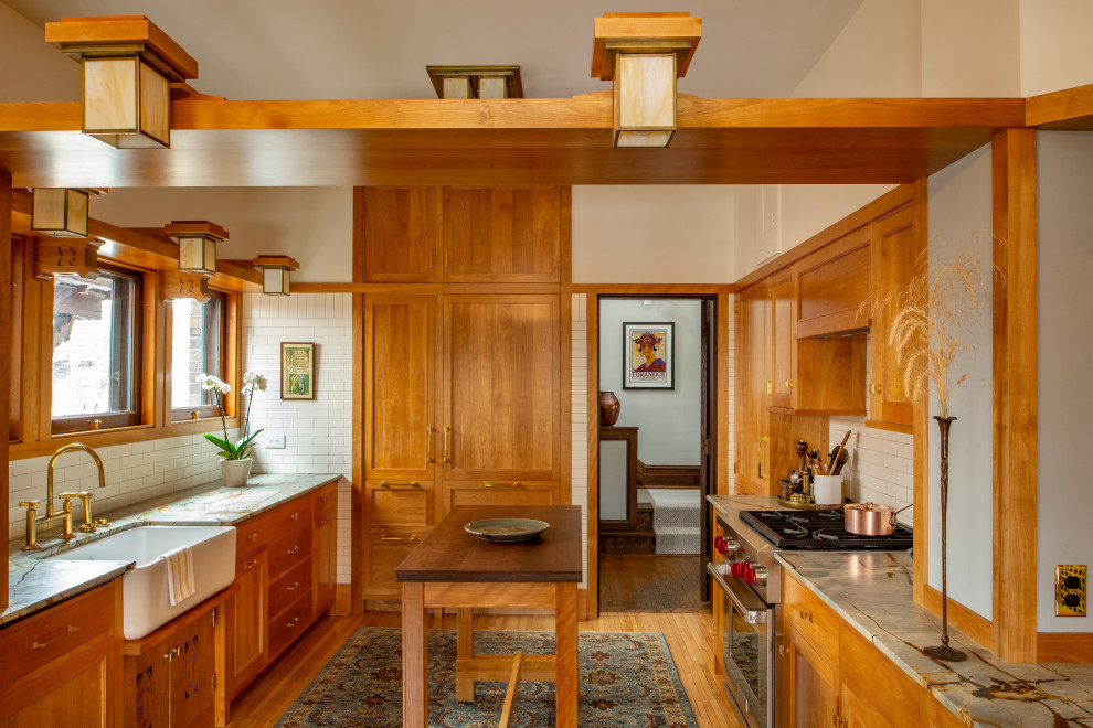 Arts and crafts u-shaped medium tone wood floor, brown floor and vaulted ceiling kitchen photo in Minneapolis with a farmhouse sink, shaker cabinets, medium tone wood cabinets, white backsplash, subway tile backsplash, paneled appliances, an island and gray countertops