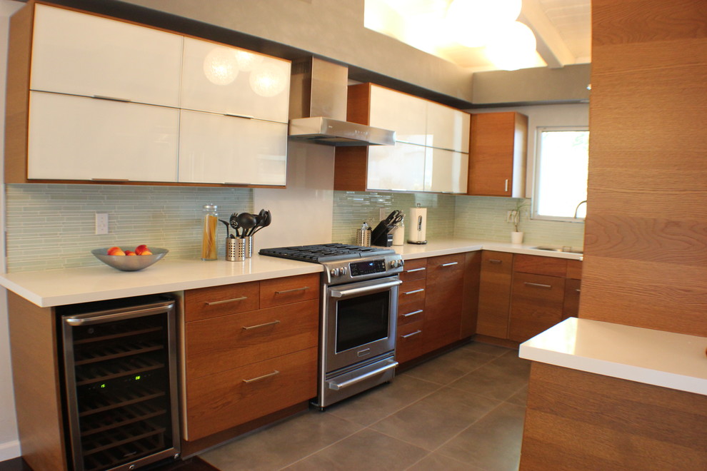 Bild på ett 50 tals kök, med en undermonterad diskho, luckor med glaspanel, vita skåp, bänkskiva i kvartsit, vitt stänkskydd och rostfria vitvaror