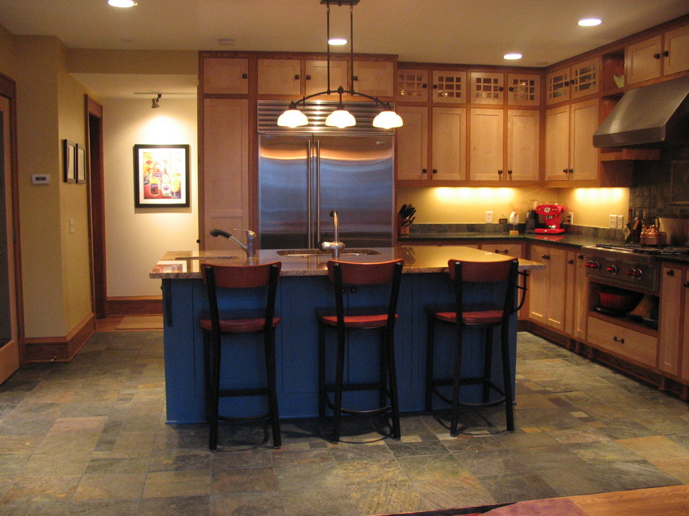 This is an example of a medium sized traditional l-shaped kitchen/diner in Minneapolis with a submerged sink, recessed-panel cabinets, medium wood cabinets, granite worktops, grey splashback, stainless steel appliances, slate flooring and an island.