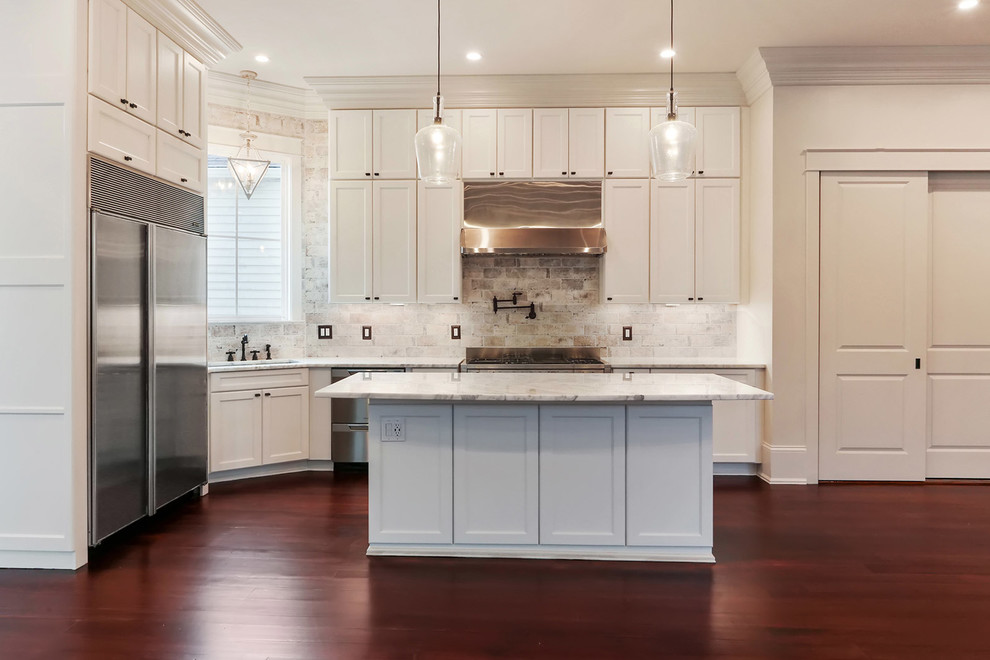 Design ideas for a medium sized classic l-shaped kitchen in New Orleans with a submerged sink, recessed-panel cabinets, white cabinets, marble worktops, beige splashback, brick splashback, stainless steel appliances, dark hardwood flooring and an island.
