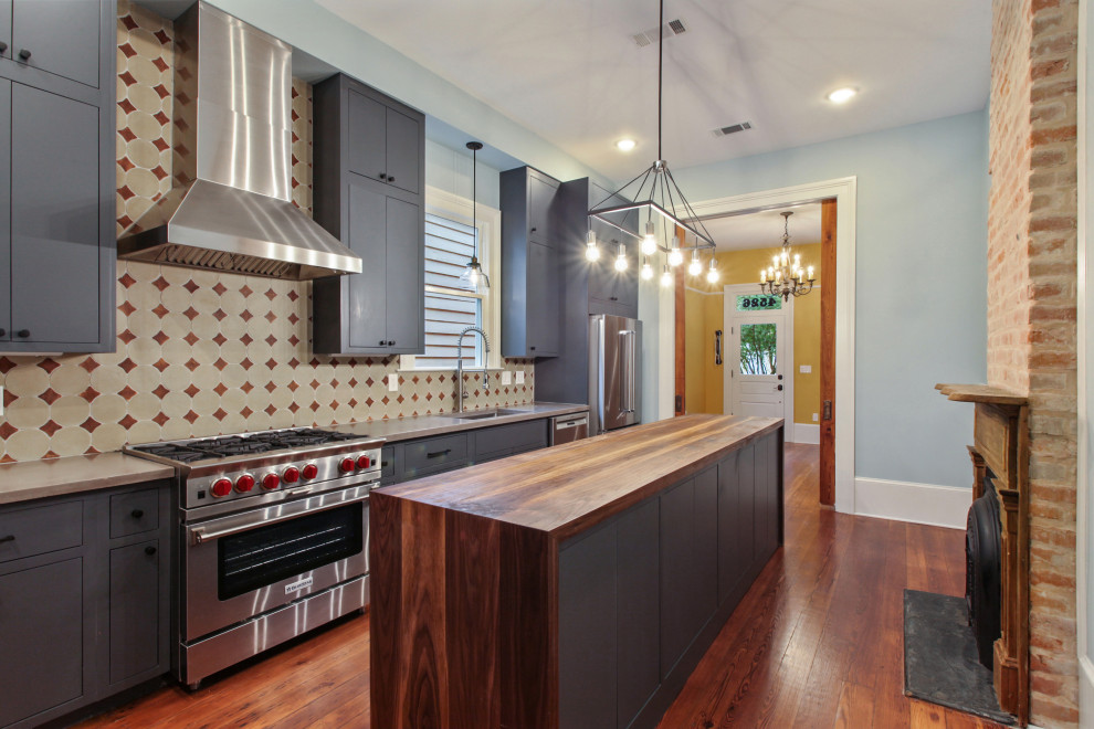 ニューオリンズにあるラグジュアリーな中くらいなトランジショナルスタイルのおしゃれなキッチン (ドロップインシンク、フラットパネル扉のキャビネット、青いキャビネット、シルバーの調理設備、無垢フローリング、茶色い床、ベージュのキッチンカウンター) の写真