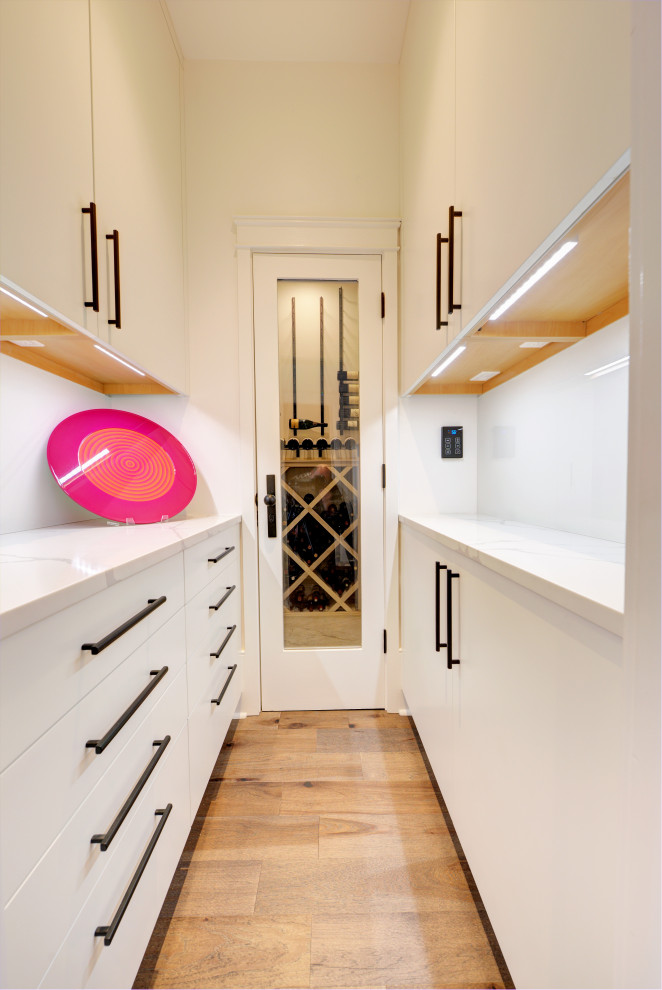 Inspiration for a medium sized contemporary l-shaped kitchen in New Orleans with flat-panel cabinets, blue cabinets, white splashback, integrated appliances, medium hardwood flooring, an island and white worktops.
