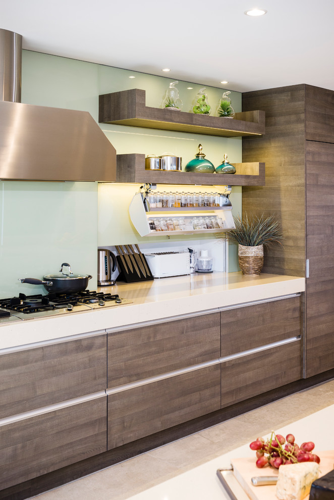 Design ideas for a large modern galley open plan kitchen in Melbourne with a double-bowl sink, flat-panel cabinets, brown cabinets, engineered stone countertops, green splashback, glass sheet splashback, integrated appliances, concrete flooring, an island and beige floors.