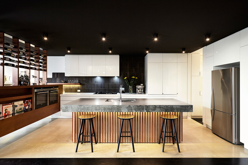 Large contemporary u-shaped kitchen in Melbourne with a submerged sink, flat-panel cabinets, white cabinets, black splashback, stainless steel appliances and an island.