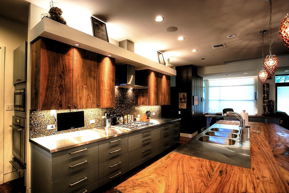 Photo of a large eclectic galley open plan kitchen in Austin with a triple-bowl sink, flat-panel cabinets, medium wood cabinets, wood worktops, multi-coloured splashback, stainless steel appliances and medium hardwood flooring.