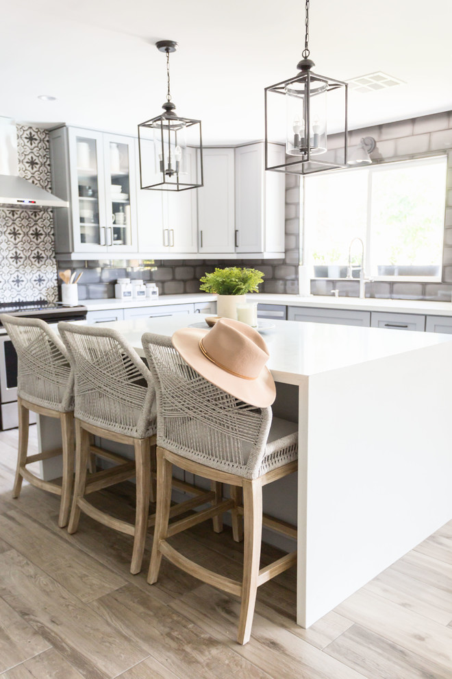 Exempel på ett mellanstort klassiskt vit vitt kök, med en undermonterad diskho, luckor med infälld panel, grå skåp, bänkskiva i kvarts, flerfärgad stänkskydd, stänkskydd i keramik, rostfria vitvaror, ljust trägolv, en köksö och grått golv
