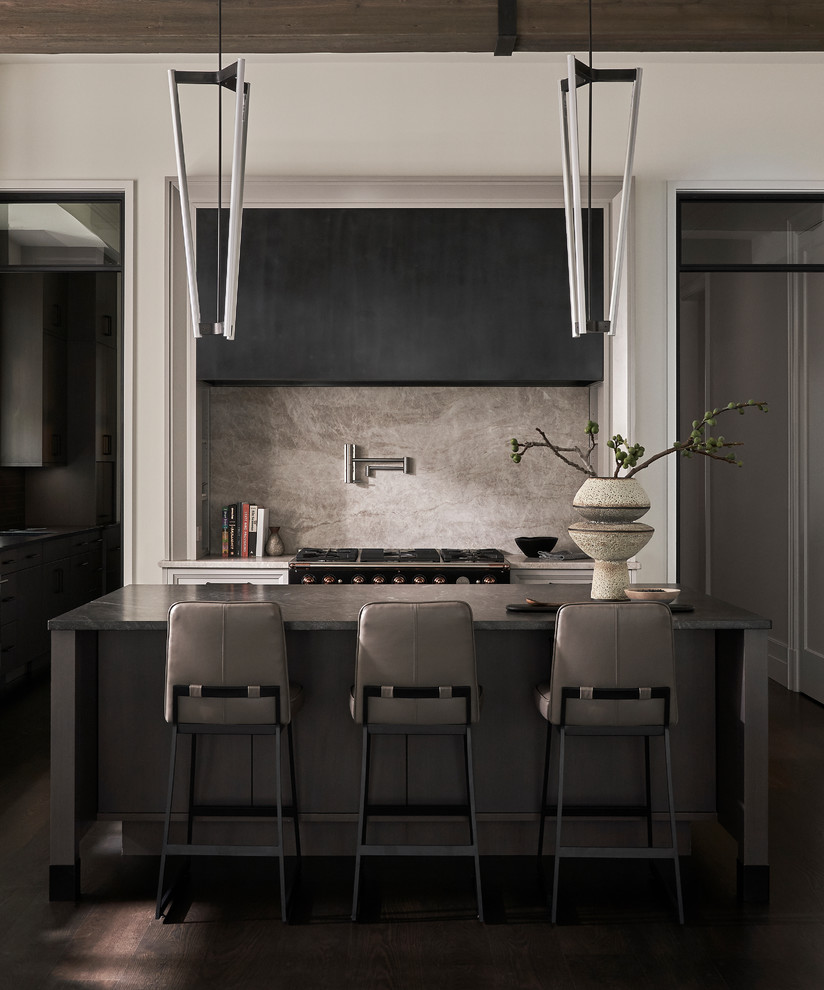 Klassische Küche mit Küchenrückwand in Grau, Rückwand aus Stein, schwarzen Elektrogeräten, dunklem Holzboden, Kücheninsel und schwarzer Arbeitsplatte in Chicago