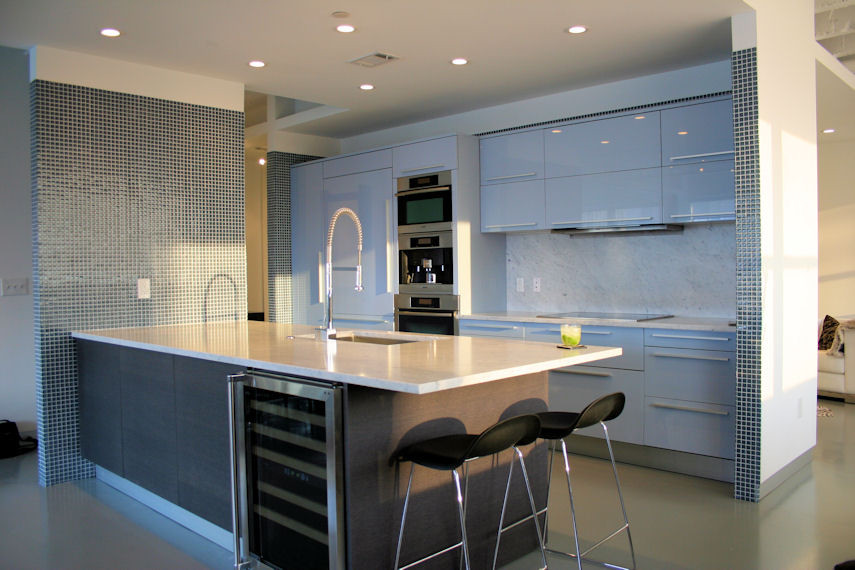 Eat-in kitchen - mid-sized modern galley concrete floor eat-in kitchen idea in Atlanta with an undermount sink, flat-panel cabinets, blue cabinets, quartzite countertops, white backsplash, stone slab backsplash, paneled appliances and an island