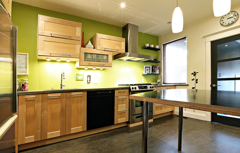 Foto på ett avskilt, mellanstort funkis l-kök, med en undermonterad diskho, luckor med infälld panel, skåp i ljust trä, bänkskiva i betong, grönt stänkskydd, rostfria vitvaror och linoleumgolv