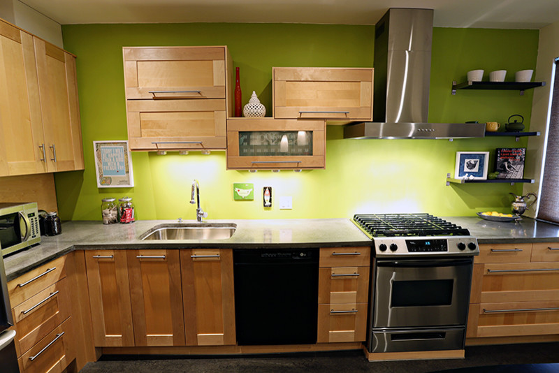 Bild på ett avskilt, mellanstort funkis l-kök, med en undermonterad diskho, luckor med infälld panel, skåp i ljust trä, bänkskiva i betong, grönt stänkskydd, rostfria vitvaror och linoleumgolv