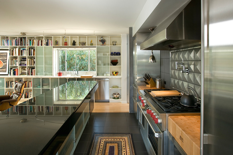 Inspiration för ett mellanstort funkis kök, med granitbänkskiva, stänkskydd med metallisk yta, stänkskydd i metallkakel, rostfria vitvaror, en köksö och svart golv