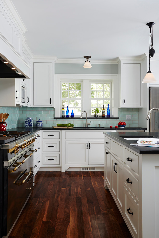 Foto på ett mellanstort, avskilt vintage l-kök, med en undermonterad diskho, luckor med profilerade fronter, vita skåp, mörkt trägolv, en köksö, bänkskiva i kvartsit, blått stänkskydd, stänkskydd i keramik och rostfria vitvaror