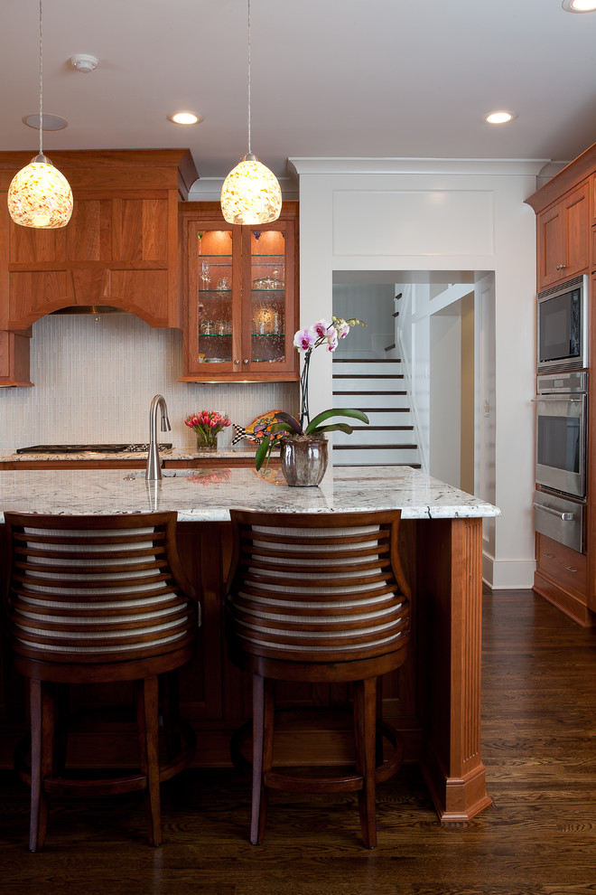 This is an example of a medium sized traditional enclosed kitchen in Atlanta with recessed-panel cabinets, medium wood cabinets, beige splashback, matchstick tiled splashback, a double-bowl sink, granite worktops, integrated appliances, dark hardwood flooring and an island.