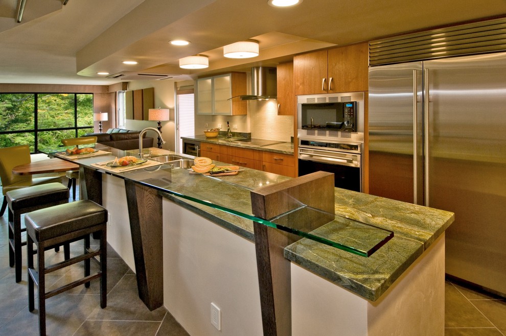 Zweizeilige Moderne Küche mit flächenbündigen Schrankfronten, Küchengeräten aus Edelstahl, Glas-Arbeitsplatte, Doppelwaschbecken, hellbraunen Holzschränken und grüner Arbeitsplatte in Hawaii