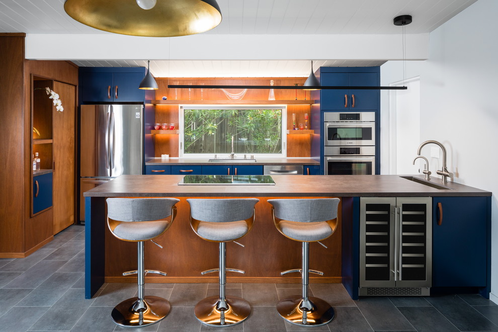 Foto di una cucina minimalista con lavello sottopiano, ante lisce, ante blu, elettrodomestici in acciaio inossidabile, pavimento grigio e top grigio