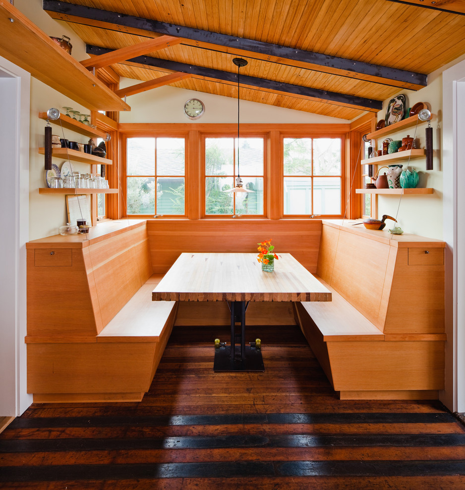 Cette photo montre une cuisine américaine éclectique en bois clair et L avec un placard à porte plane et un sol en bois brun.