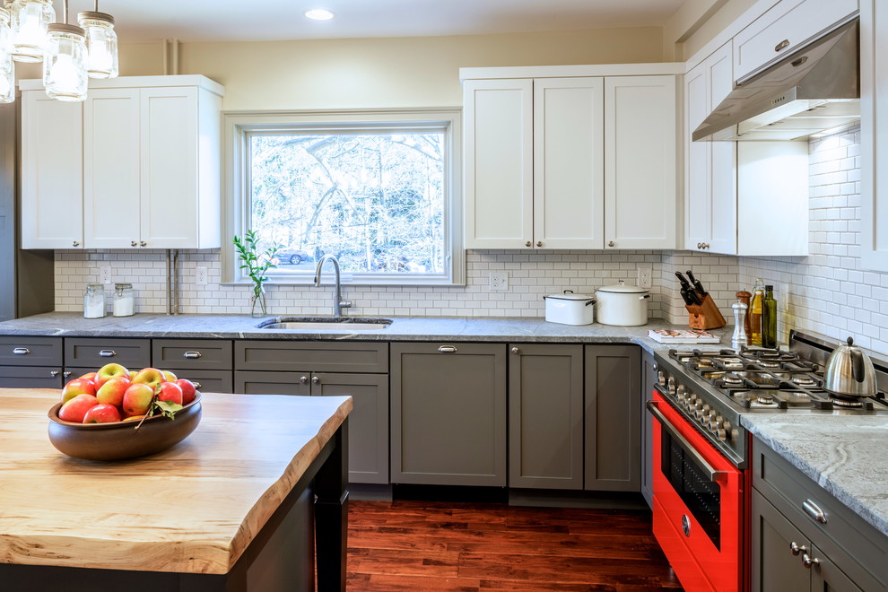 Example of a large farmhouse l-shaped dark wood floor enclosed kitchen design in New York with an undermount sink, gray cabinets, solid surface countertops, white backsplash, subway tile backsplash, colored appliances, an island and shaker cabinets