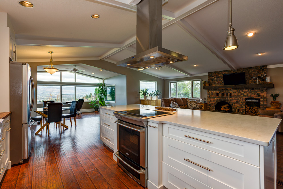 Inspiration for a large contemporary single-wall open plan kitchen in Vancouver with shaker cabinets, white cabinets, stainless steel appliances, medium hardwood flooring, an island and granite worktops.