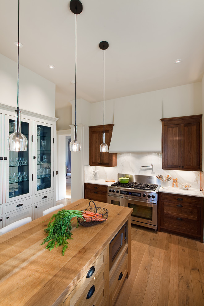 Inspiration for a timeless enclosed kitchen remodel in Austin with stainless steel appliances, wood countertops, dark wood cabinets, white backsplash and stone slab backsplash