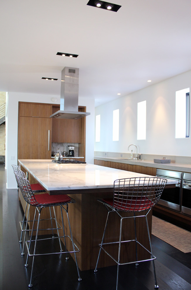 Cette photo montre une cuisine ouverte parallèle et encastrable moderne en bois clair avec un placard à porte plane et plan de travail en marbre.