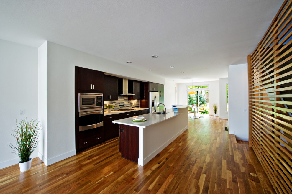 Immagine di un cucina con isola centrale minimalista con ante lisce e ante in legno bruno