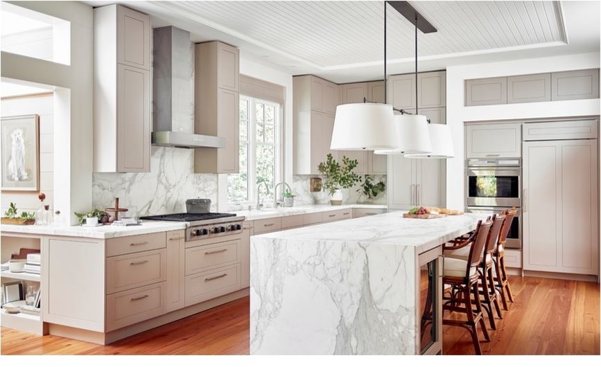 Inredning av ett modernt stort vit vitt kök, med luckor med upphöjd panel, beige skåp, marmorbänkskiva, vitt stänkskydd, stänkskydd i marmor, rostfria vitvaror, mellanmörkt trägolv, en köksö och brunt golv