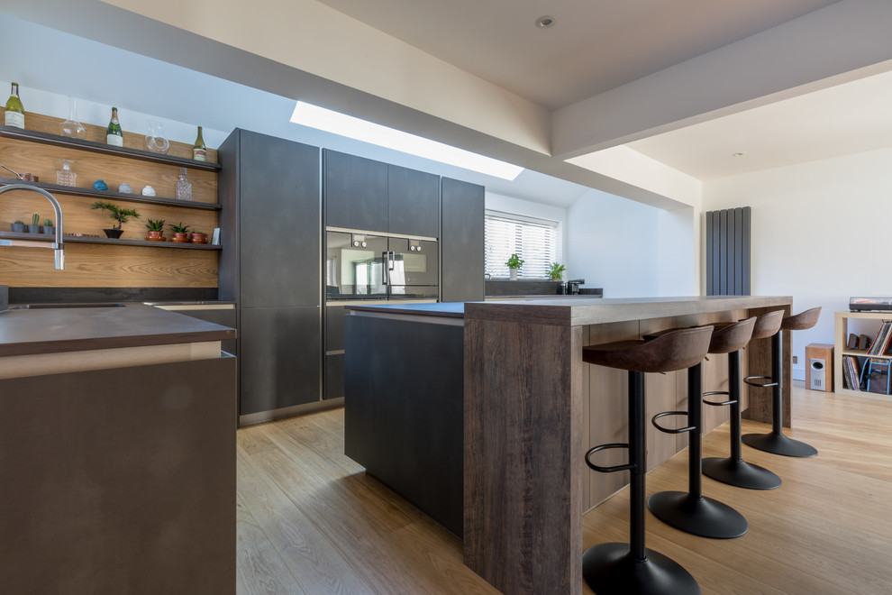 Inspiration for a medium sized urban galley open plan kitchen in Sussex with flat-panel cabinets, grey cabinets, tile countertops, an island and grey worktops.
