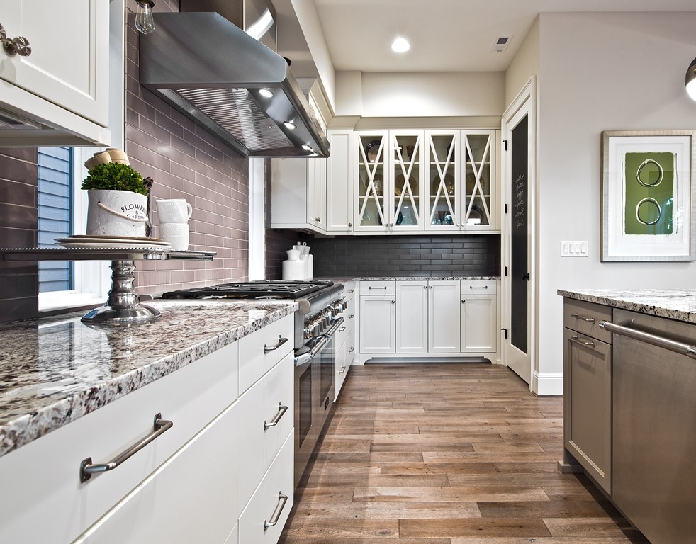 Open concept kitchen - large transitional l-shaped medium tone wood floor open concept kitchen idea in Seattle with an undermount sink, shaker cabinets, white cabinets, granite countertops, brown backsplash, subway tile backsplash, stainless steel appliances and an island