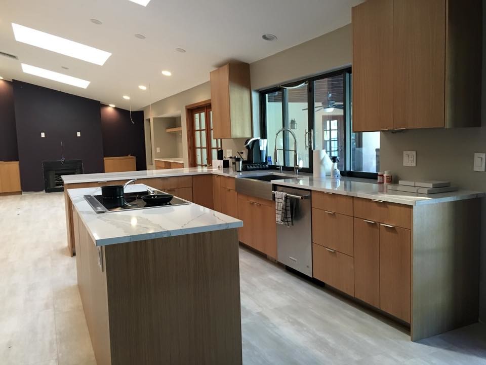 This is an example of a large contemporary l-shaped open plan kitchen in Miami with a belfast sink, flat-panel cabinets, stainless steel appliances, porcelain flooring, an island, light wood cabinets and quartz worktops.