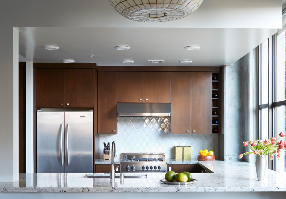 Exempel på ett mellanstort modernt kök, med en undermonterad diskho, släta luckor, skåp i mellenmörkt trä, granitbänkskiva, vitt stänkskydd, stänkskydd i mosaik, rostfria vitvaror och ljust trägolv
