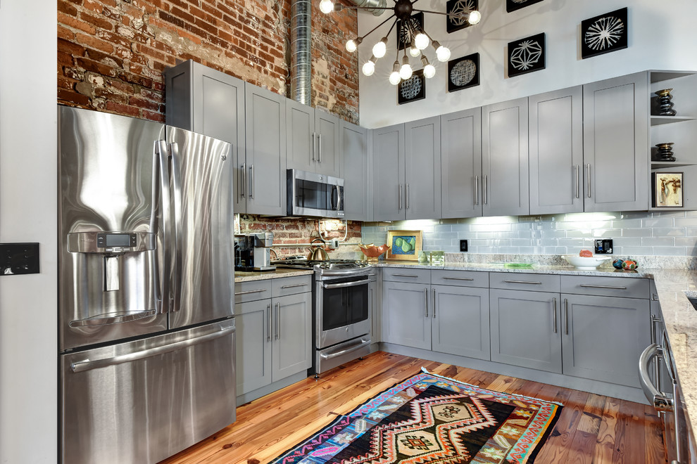 Kitchen - industrial u-shaped medium tone wood floor kitchen idea in Charleston with shaker cabinets, gray cabinets, gray backsplash, subway tile backsplash, stainless steel appliances and multicolored countertops