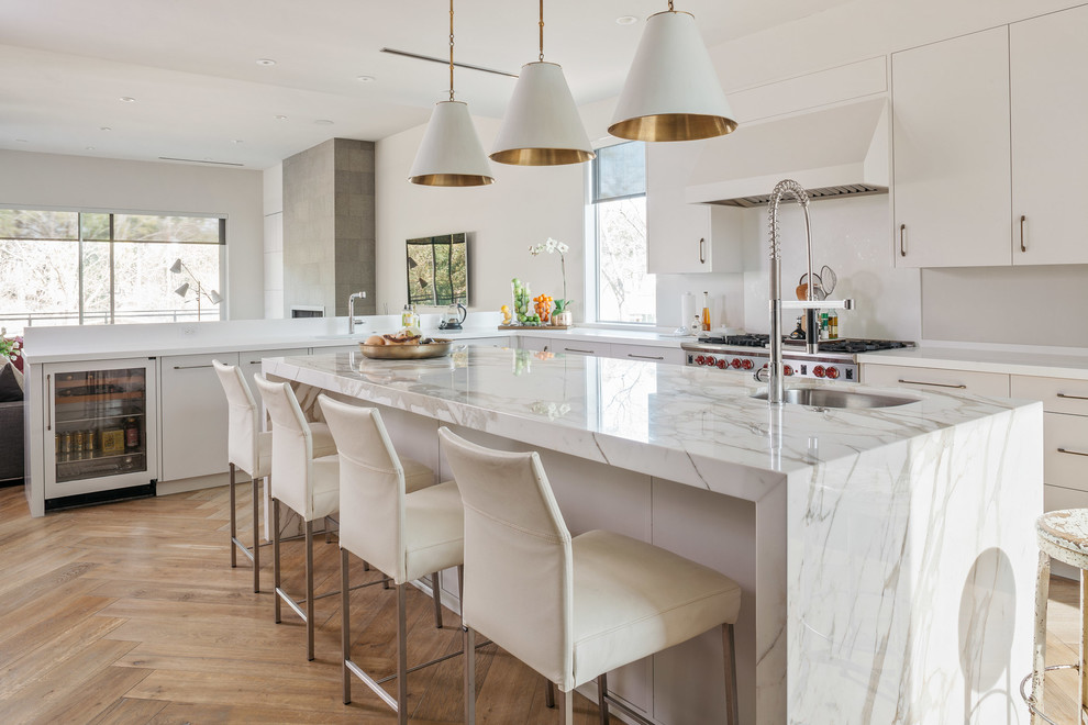 Trendy l-shaped medium tone wood floor and beige floor kitchen photo in Houston with an undermount sink, flat-panel cabinets, white cabinets, white backsplash, stainless steel appliances and an island