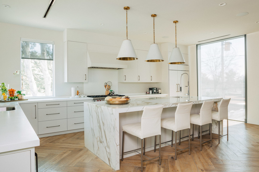 Idee per un cucina con isola centrale minimal con ante lisce, ante bianche, top in quarzite, pavimento in legno massello medio e pavimento marrone