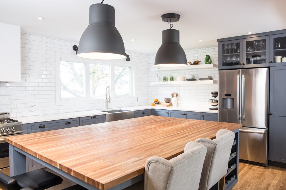 Exempel på ett mellanstort modernt kök, med en rustik diskho, skåp i shakerstil, grå skåp, bänkskiva i kvartsit, vitt stänkskydd, stänkskydd i tunnelbanekakel, rostfria vitvaror, mellanmörkt trägolv och en köksö