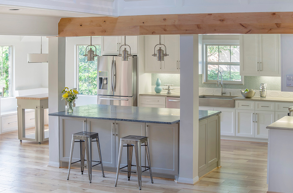 Eat-in kitchen - large modern l-shaped light wood floor and brown floor eat-in kitchen idea in Other with a farmhouse sink, white cabinets, soapstone countertops, green backsplash, subway tile backsplash, stainless steel appliances, two islands and recessed-panel cabinets