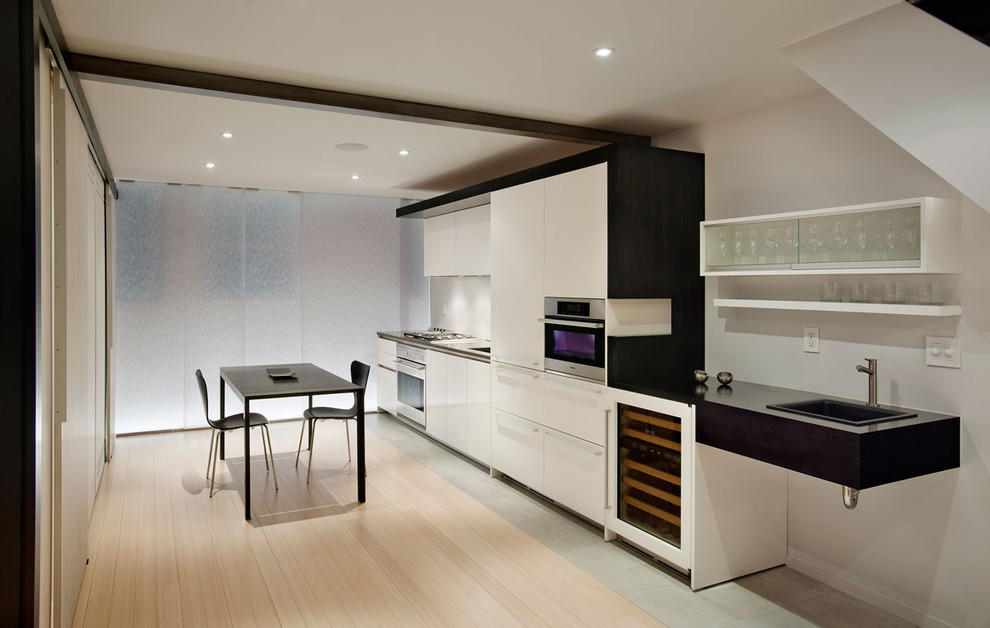Idées déco pour une cuisine linéaire contemporaine avec un placard à porte plane, des portes de placard blanches et un électroménager blanc.