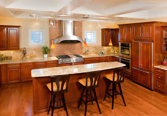 Foto på ett mellanstort vintage beige u-kök, med luckor med upphöjd panel, skåp i mörkt trä, granitbänkskiva, brunt stänkskydd, stänkskydd i stenkakel, integrerade vitvaror, mellanmörkt trägolv, en köksö och brunt golv