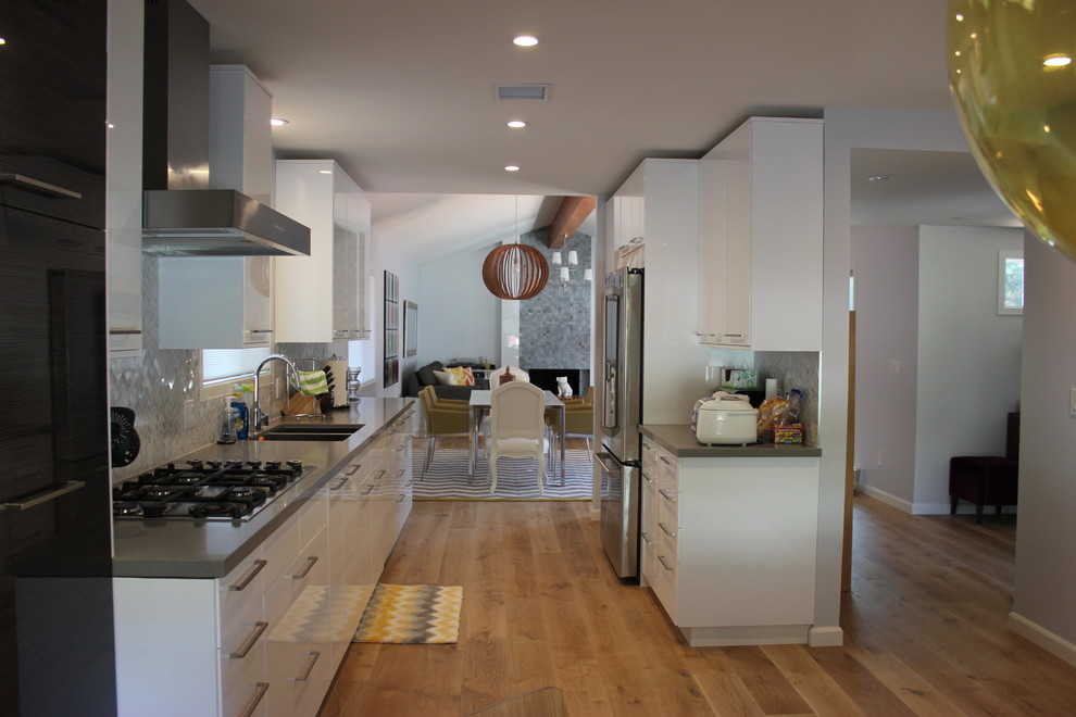 Minimalist galley eat-in kitchen photo in Los Angeles with an undermount sink, flat-panel cabinets, white cabinets, quartzite countertops, white backsplash, mosaic tile backsplash and stainless steel appliances