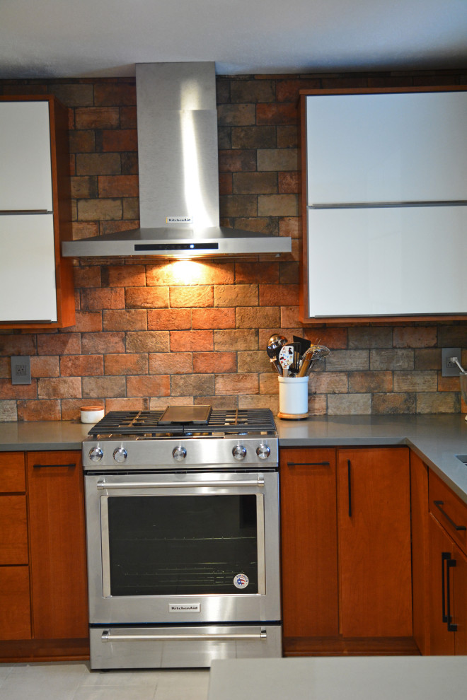 Bild på ett mellanstort funkis grå grått kök, med en undermonterad diskho, släta luckor, skåp i mellenmörkt trä, bänkskiva i kvarts, flerfärgad stänkskydd, stänkskydd i stenkakel, rostfria vitvaror, klinkergolv i keramik, en halv köksö och grått golv