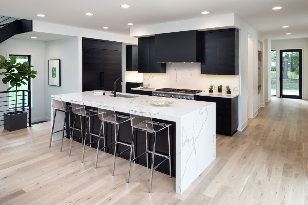 Inspiration for a large industrial l-shaped light wood floor eat-in kitchen remodel in Minneapolis with an undermount sink, flat-panel cabinets, dark wood cabinets, quartz countertops, white backsplash, paneled appliances, an island and white countertops