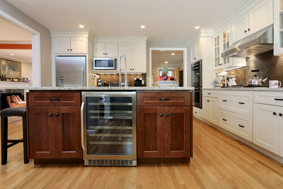 Inspiration for a mid-sized farmhouse l-shaped light wood floor and beige floor eat-in kitchen remodel in Boston with an undermount sink, shaker cabinets, white cabinets, granite countertops, brown backsplash, porcelain backsplash, stainless steel appliances and an island