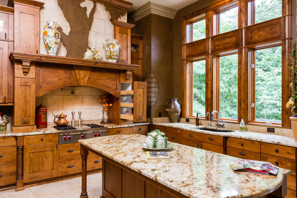 Cette image montre une cuisine chalet en L et bois brun avec un évier encastré, un placard à porte shaker, une crédence beige, un électroménager en acier inoxydable et îlot.