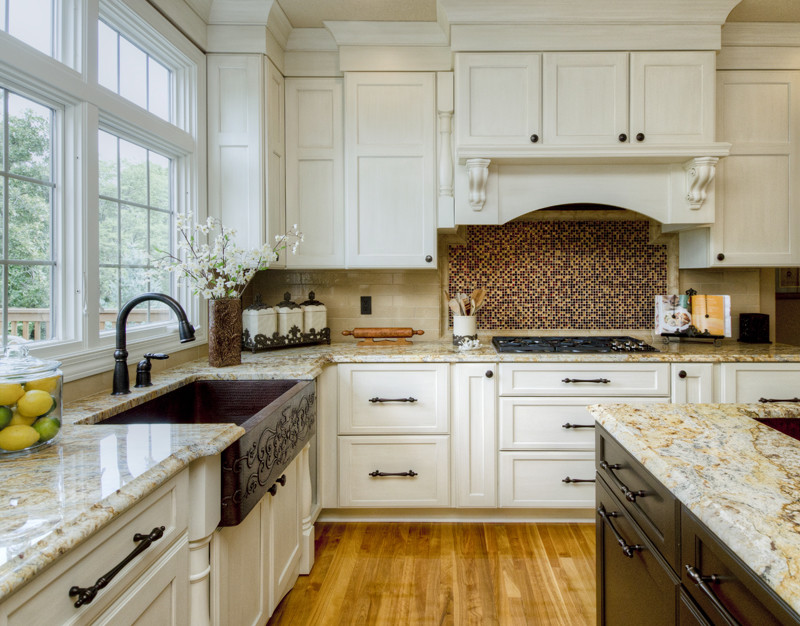 Example of a large classic single-wall medium tone wood floor kitchen pantry design in Other with a farmhouse sink, shaker cabinets, white cabinets, granite countertops, beige backsplash, ceramic backsplash, black appliances and no island