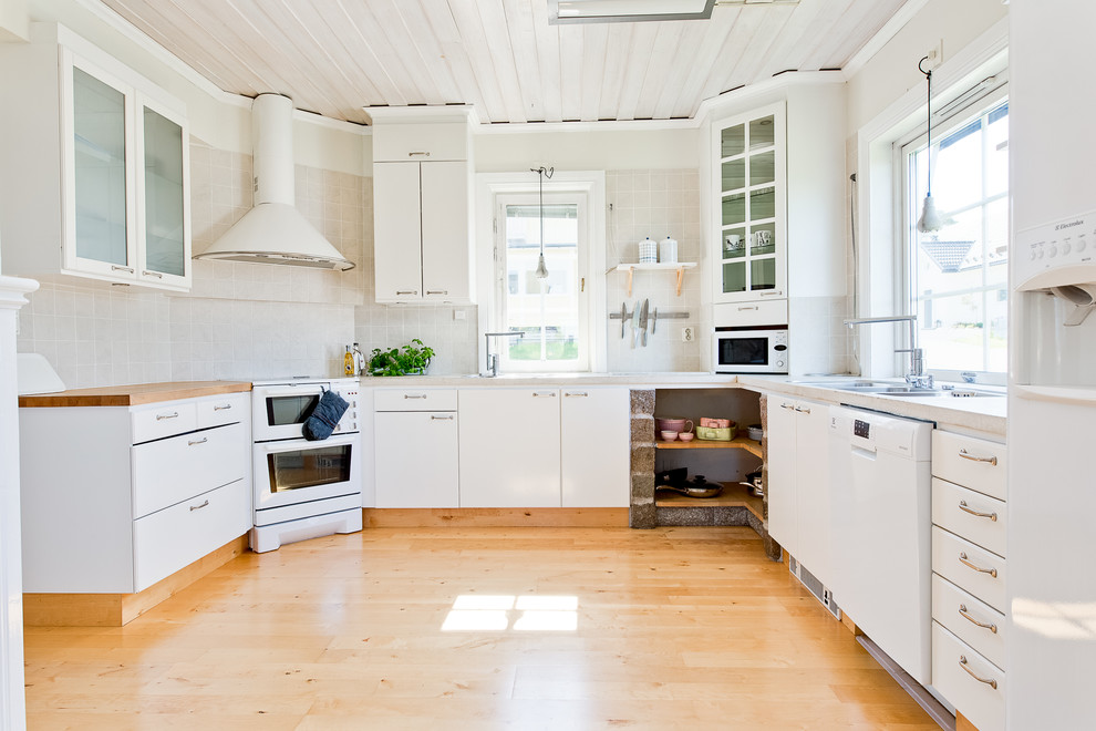 Exempel på ett mellanstort nordiskt beige beige kök, med en undermonterad diskho, släta luckor, vita skåp, träbänkskiva, vitt stänkskydd, stänkskydd i keramik, vita vitvaror, ljust trägolv och beiget golv